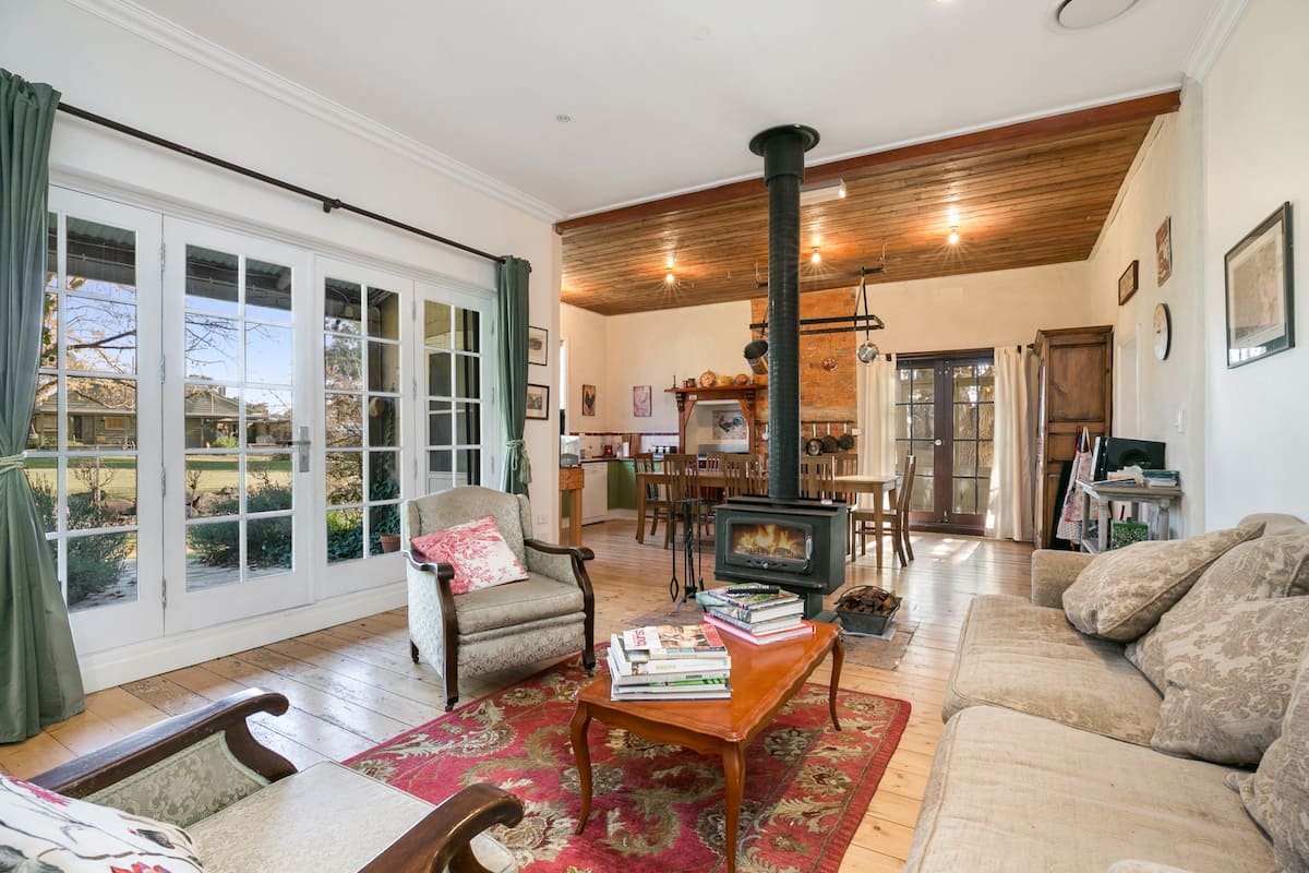 Una sala de estar acogedora con chimenea, zona de comedor y ventanas amplias.