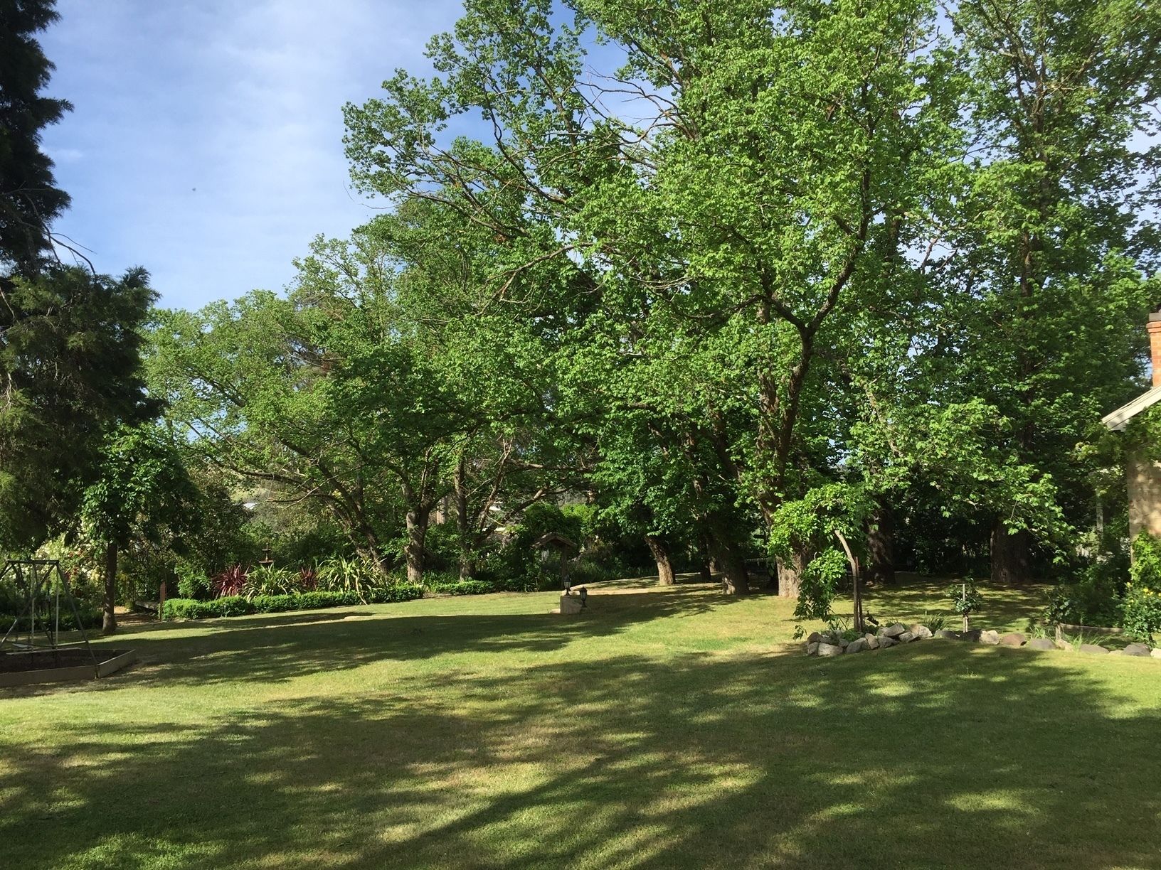 A well-maintained garden with mature trees, a lawn, and a stone pathway.