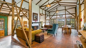 Un interior rústico con vigas de madera a la vista, chimenea, comedor y sofá.