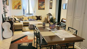 Una sala de estar con sofá, mesa de comedor, mesa de centro y piano.
