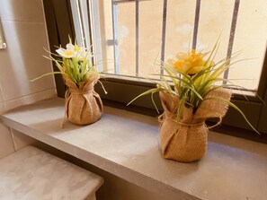 Twee vazen, omwikkeld met jute, met bloemen op een vensterbank.