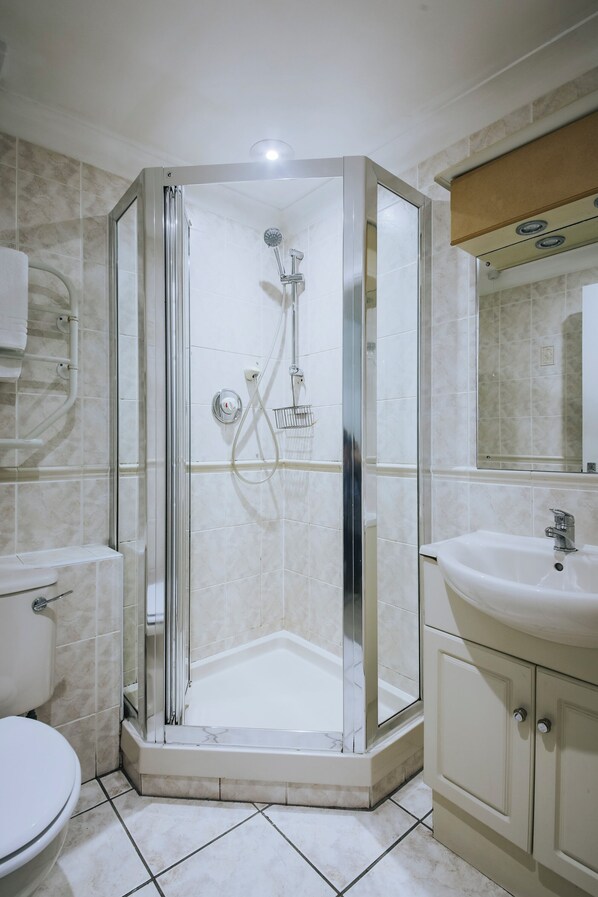 Une salle de bain moderne avec une douche à parois de verre, un lavabo blanc et des toilettes.