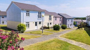A row of two-story houses with a paved walkway and a picnic table in the foreground. - Atlantic Reach Cottage, Newquay.  Large 4 bed villa with leisure services & WiFi (Newquay)