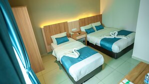 A hotel room with two beds, each with a blue and white duvet, a wooden headboard, and a bedside table with a phone and a lamp. - Alaxis Hotel (Kuala Lumpur)