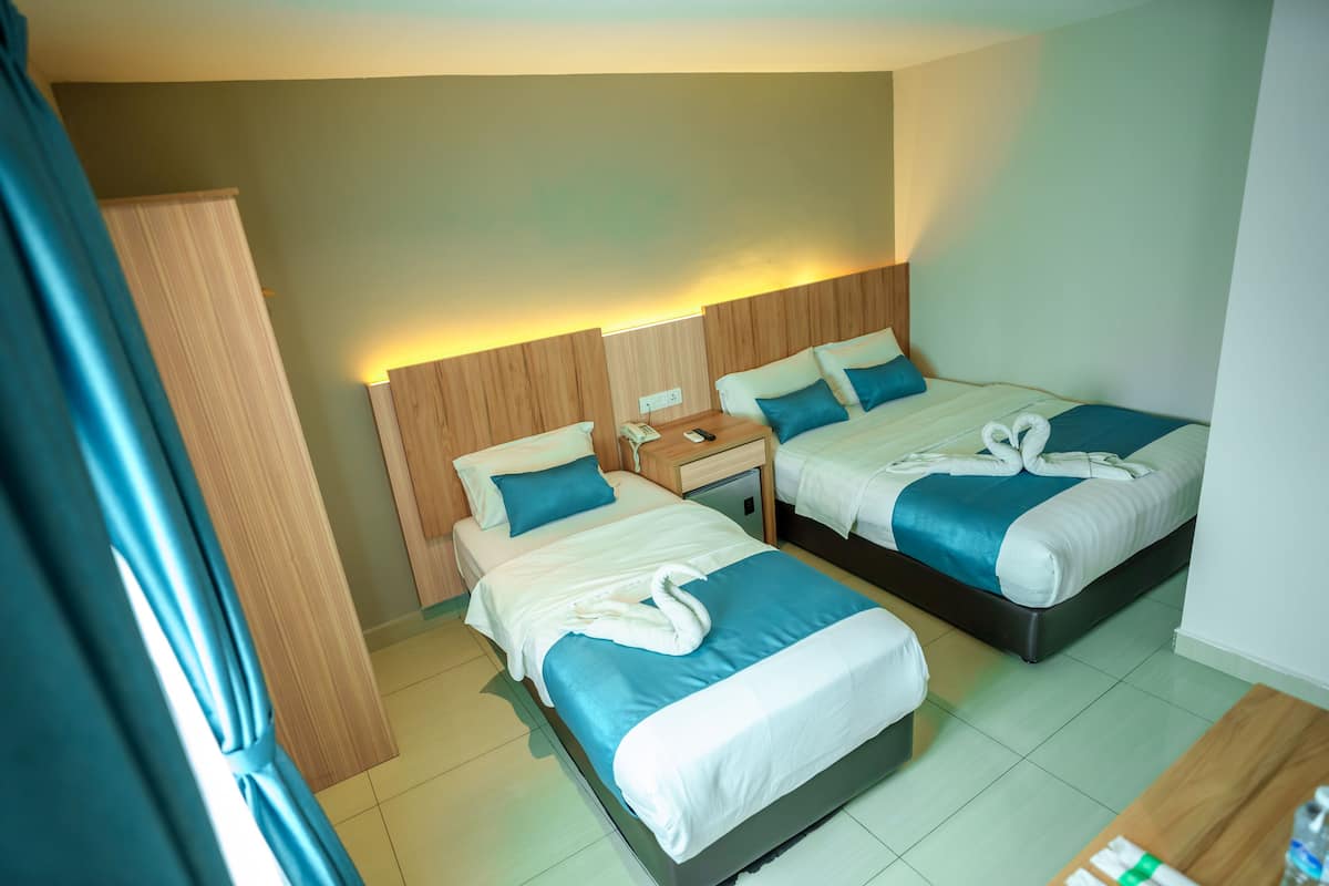 Habitación de hotel con dos camas, cada una con cubrecama azul y blanco, cabecero de madera y mesita de noche con teléfono y lámpara.