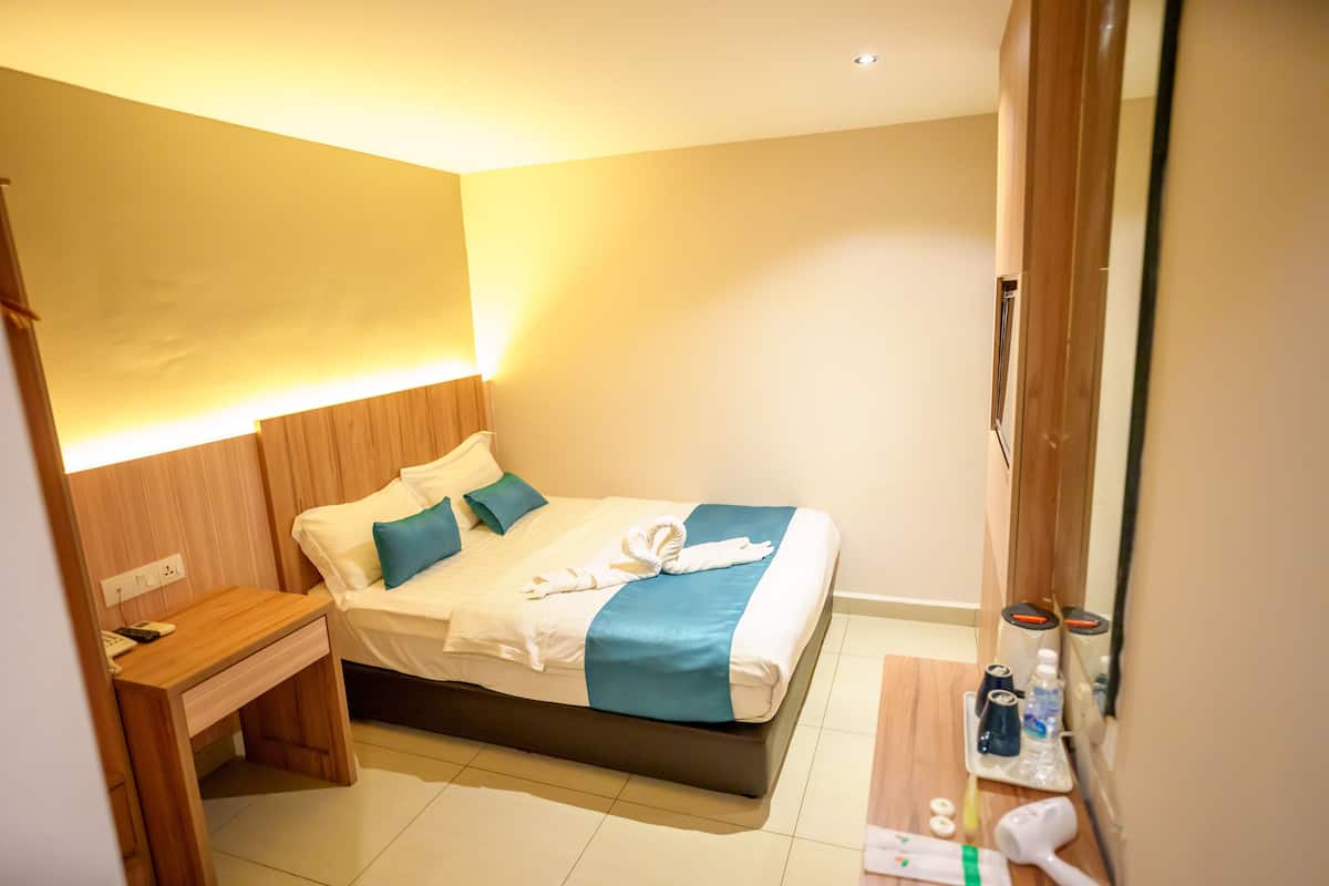 Una habitación de hotel con cama, mesita de noche y espejo.