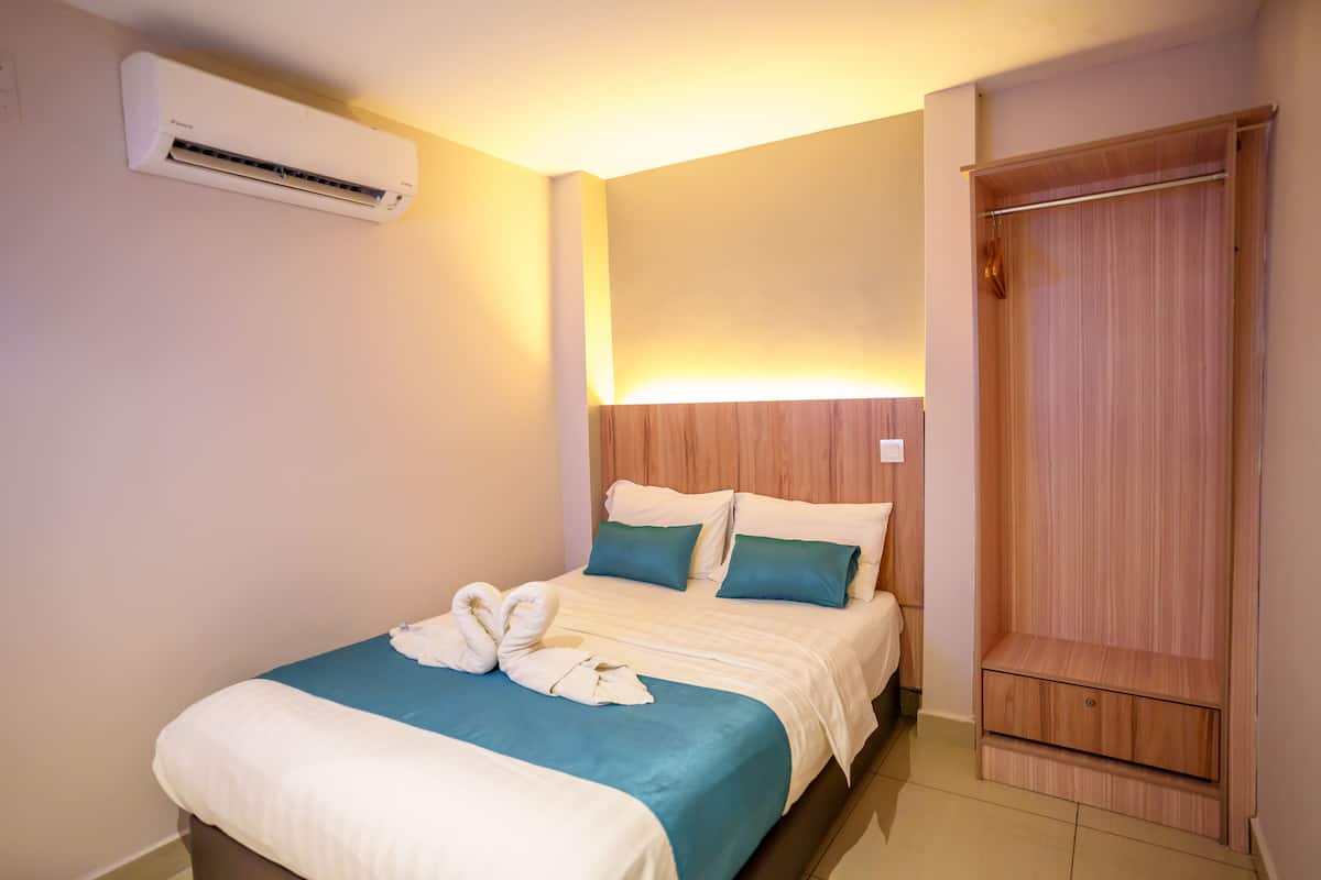 Habitación de hotel con cama, armario y aire acondicionado.