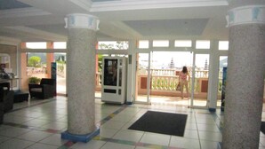 A spacious lobby with a tiled floor, a black mat at the entrance, and a view of a temple through large windows. - Residence of the Guardian Angel, Beachfront apartment, Villefranche / Mer (Villefranche-sur-Mer)
