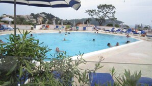 A swimming pool with people swimming and sunbathing, surrounded by lounge chairs and umbrellas. - Residence of the Guardian Angel, Beachfront apartment, Villefranche / Mer (Villefranche-sur-Mer)