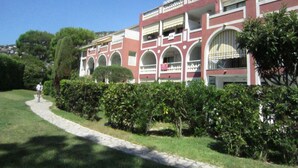 A building with a red facade, multiple arches, and a pathway leading to it. - Residence of the Guardian Angel, Beachfront apartment, Villefranche / Mer (Villefranche-sur-Mer)