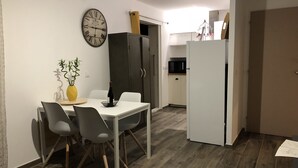 Una cucina compatta con microonde, frigorifero e zona pranzo con tavolo e sedie.