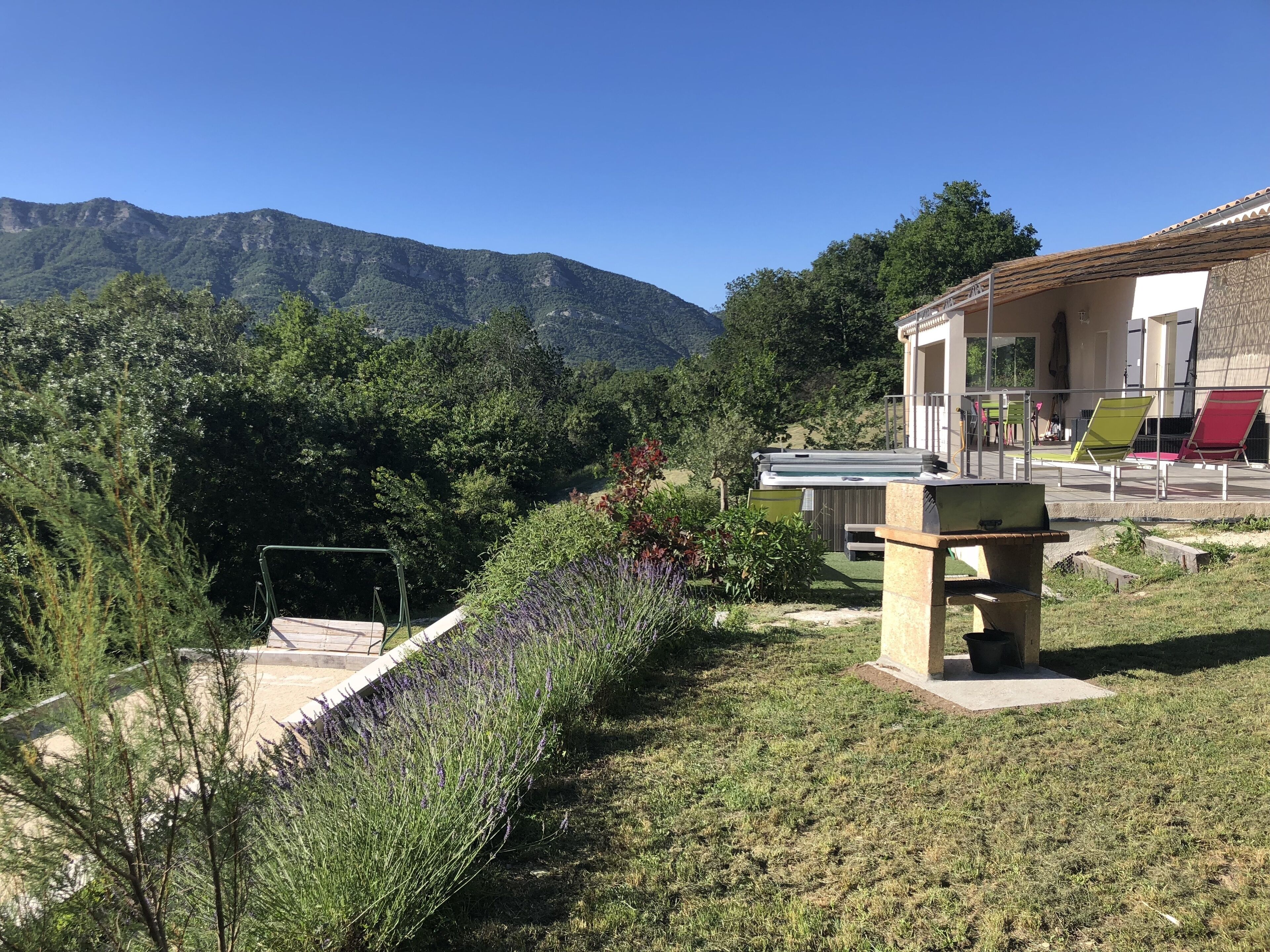 A patio area with outdoor seating, a hot tub, and a mountain backdrop.