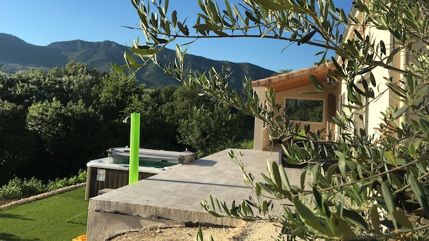 Area piscina con idromassaggio, circondata da ulivi e vista sulle montagne.