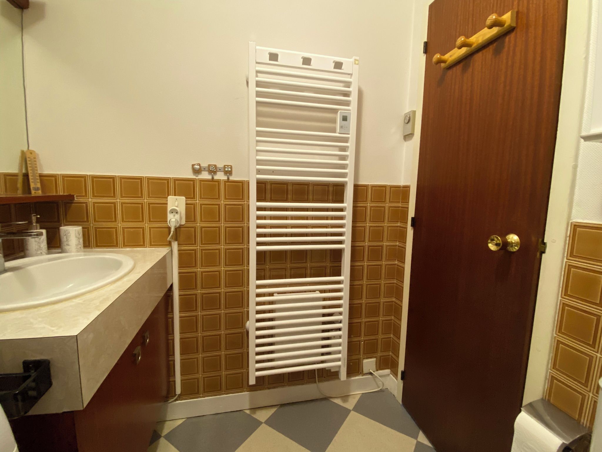 Ein Badezimmer mit weißem Waschbecken, einem Handtuchhalter und einer Tür mit Holzgriffen.