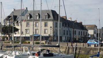 A marina with several sailboats docked. There is a building with a sign that reads "Le Skipper" and another sign that says "L'Atelier".