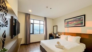 A hotel room with a large bed, a desk with a chair, a television mounted on the wall, a window with curtains, and a painting on the wall. - Central Hotel & Spa  (Da Nang)