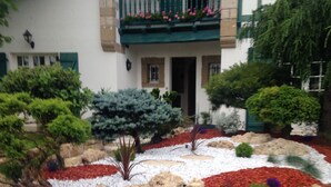Ein Haus mit Balkon, ein Garten mit verschiedenen Pflanzen und einem Kiesweg.