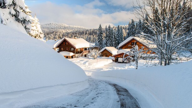 A snow-covered mountain lodge with multiple wooden cabins, a winding driveway, and a backdrop of snow-laden trees and mountains. - T2 in chalet with terrace and private parking - Montagnes du Jura (Lamoura)