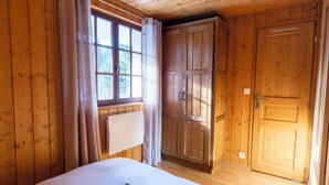 A wooden room with a bed, a wardrobe, and a window. - T2 in chalet with terrace and private parking - Montagnes du Jura (Lamoura)