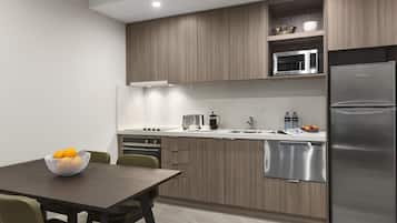 Une cuisine moderne avec des meubles en bois, des appareils électroménagers en acier inoxydable et un coin repas comprenant une table et des chaises.