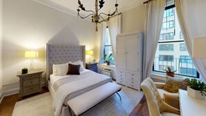 A bedroom with a large bed, bedside tables, a wardrobe, a desk with a chair, and a window with curtains. - Central Park, Theater District & Columbus Circle. New Renovation 3 Bed / 2 Bath. (New York City)