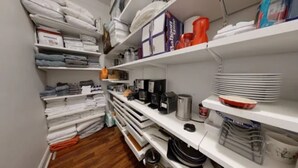 A neatly organized storage room with shelves holding folded linens, kitchenware, and storage bins. - Central Park, Theater District & Columbus Circle. New Renovation 3 Bed / 2 Bath. (New York City)