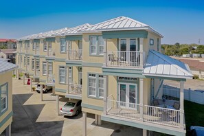 Un edificio residencial de varios pisos con balcones, una zona de estar al aire libre techada y un garaje.