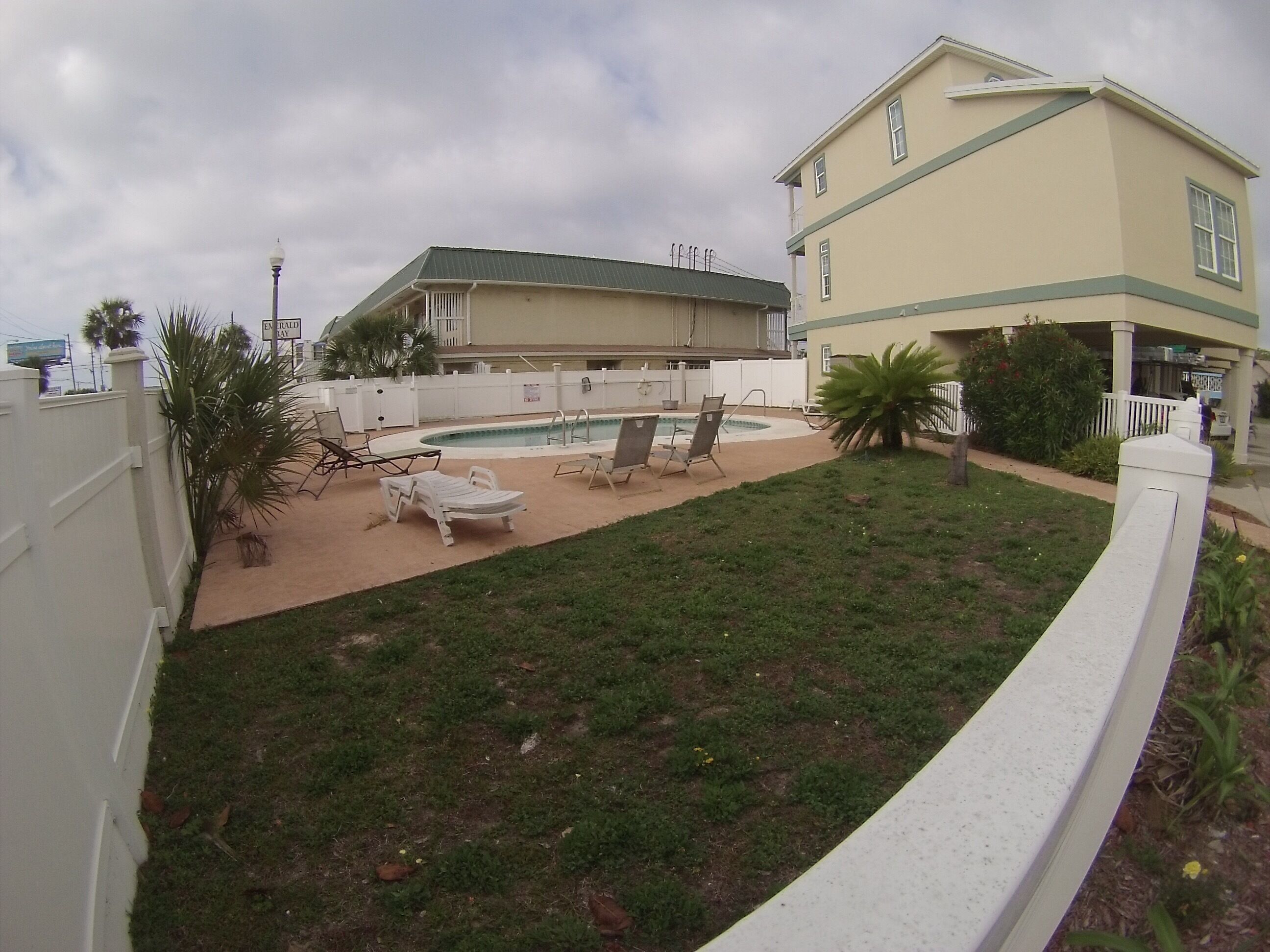 A backyard with a swimming pool, lounge chairs, and a house.