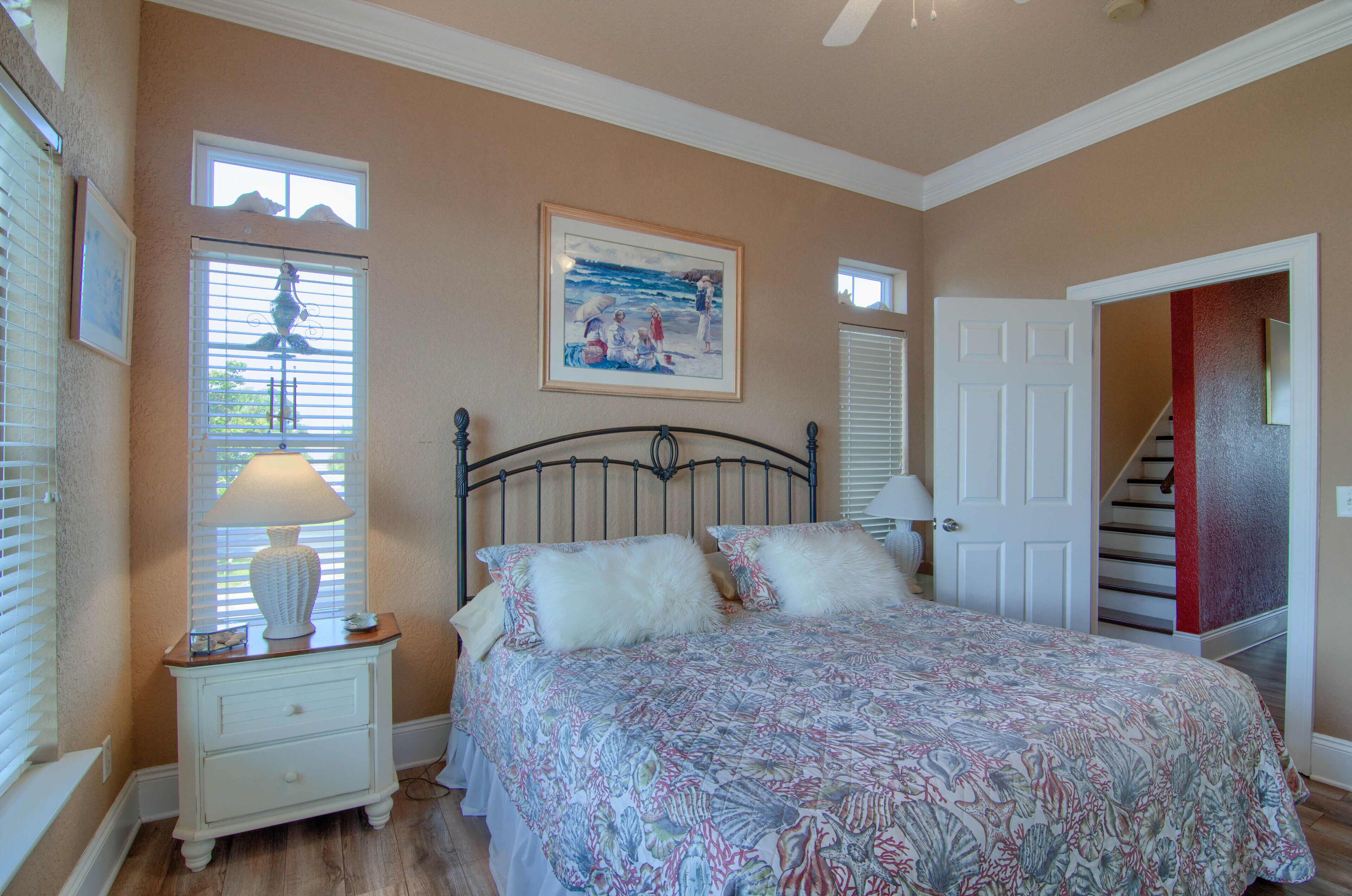 A bedroom with a bed, nightstand, and a painting on the wall.