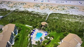 An aerial view of a resort with a central pool area, surrounded by lush greenery and a beach in the background. -  3 Bedroom Condo/ Sleeps 8 / Beautifully Upgraded (St Augustine)