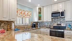 A modern kitchen with granite countertops, stainless steel appliances, and white cabinetry. -  3 Bedroom Condo/ Sleeps 8 / Beautifully Upgraded (St Augustine)
