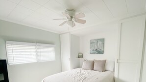 A bedroom with a bed, a ceiling fan, a window with blinds, and a door. - Lake McConaughy Cabin within walking distance to beach!  (Lewellen)