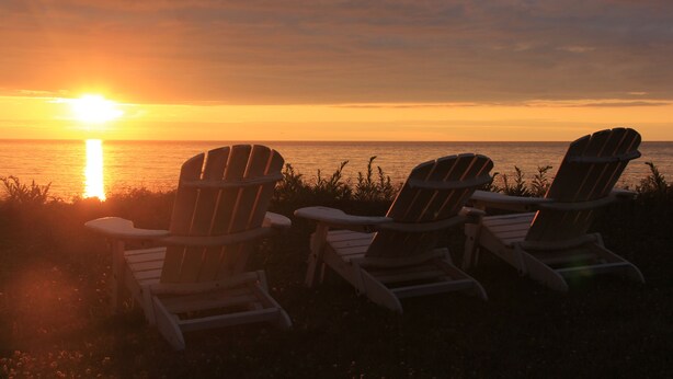 Two Adirondack chairs facing a sunset over a body of water. - Gorgeous Oceanfront Vacation Destination! (Saint Peters Bay)