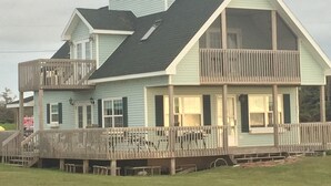 Une maison à deux étages dotée d’un balcon, d’un porche couvert et d’une petite structure en forme de tour sur le toit.