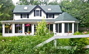A two-story house with a gabled roof, a covered porch, and a small attached gazebo. - Stream Side, Waterfalls, Catskill Getaway! (Palenville)