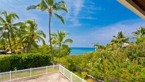 A pool area with a view of the ocean and palm trees.