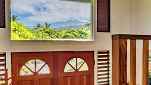 A wooden door with a view of lush greenery and mountains through a window above it.