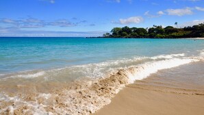 A beach with clear turquoise water, gentle waves, and a sandy shore.
