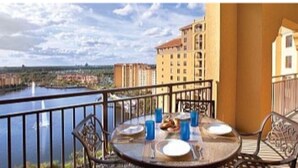 Un balcón con una mesa preparada para dos, con vista a un cuerpo de agua y edificios.
