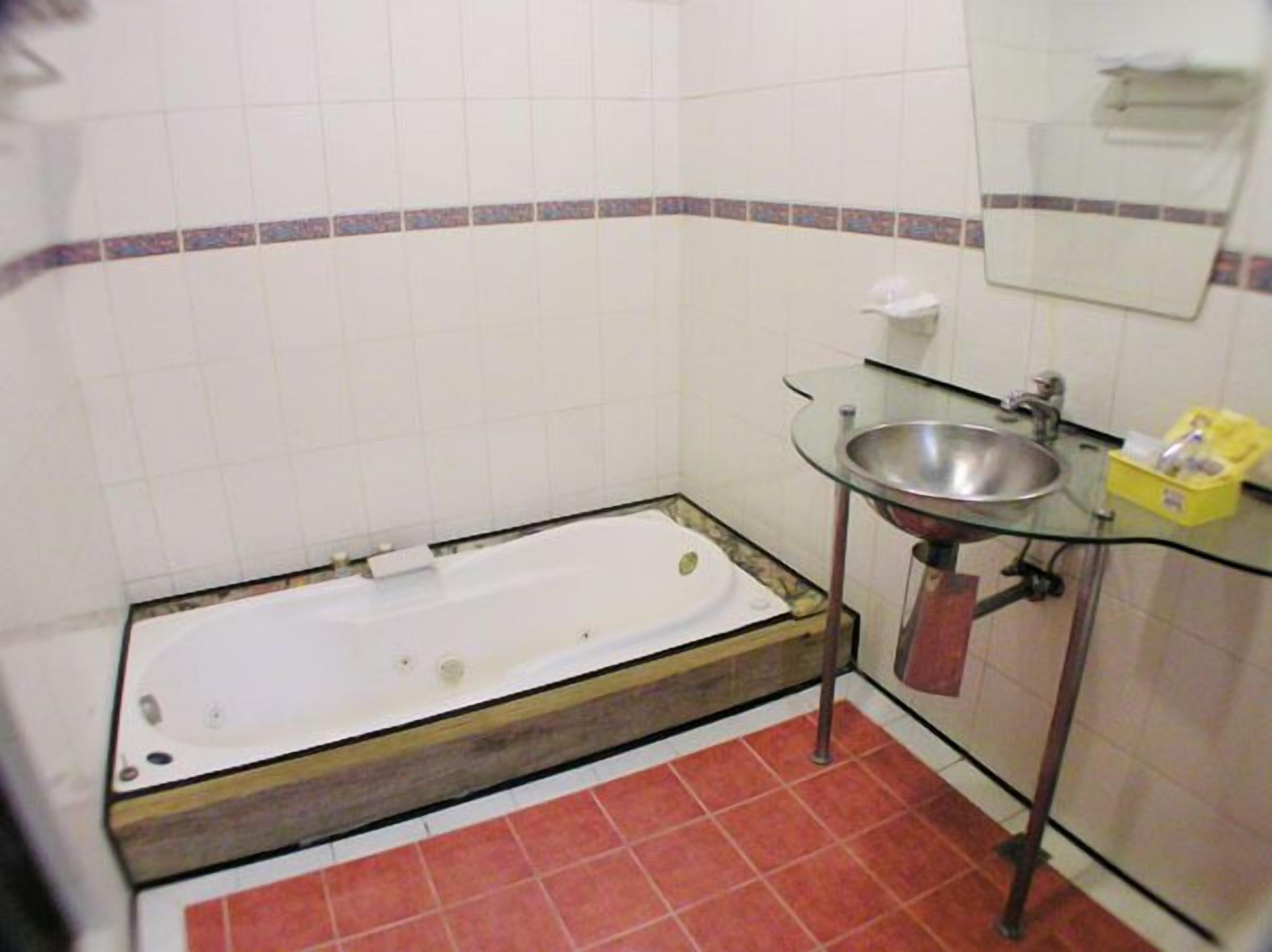 Ein Badezimmer mit Badewanne, einem Glaswaschbecken und einem Spiegel.