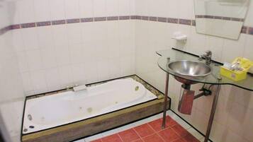 A bathroom with a bathtub, a glass sink, and a mirror.
