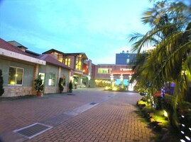 A hotel with a paved walkway, multiple buildings, and palm trees.
