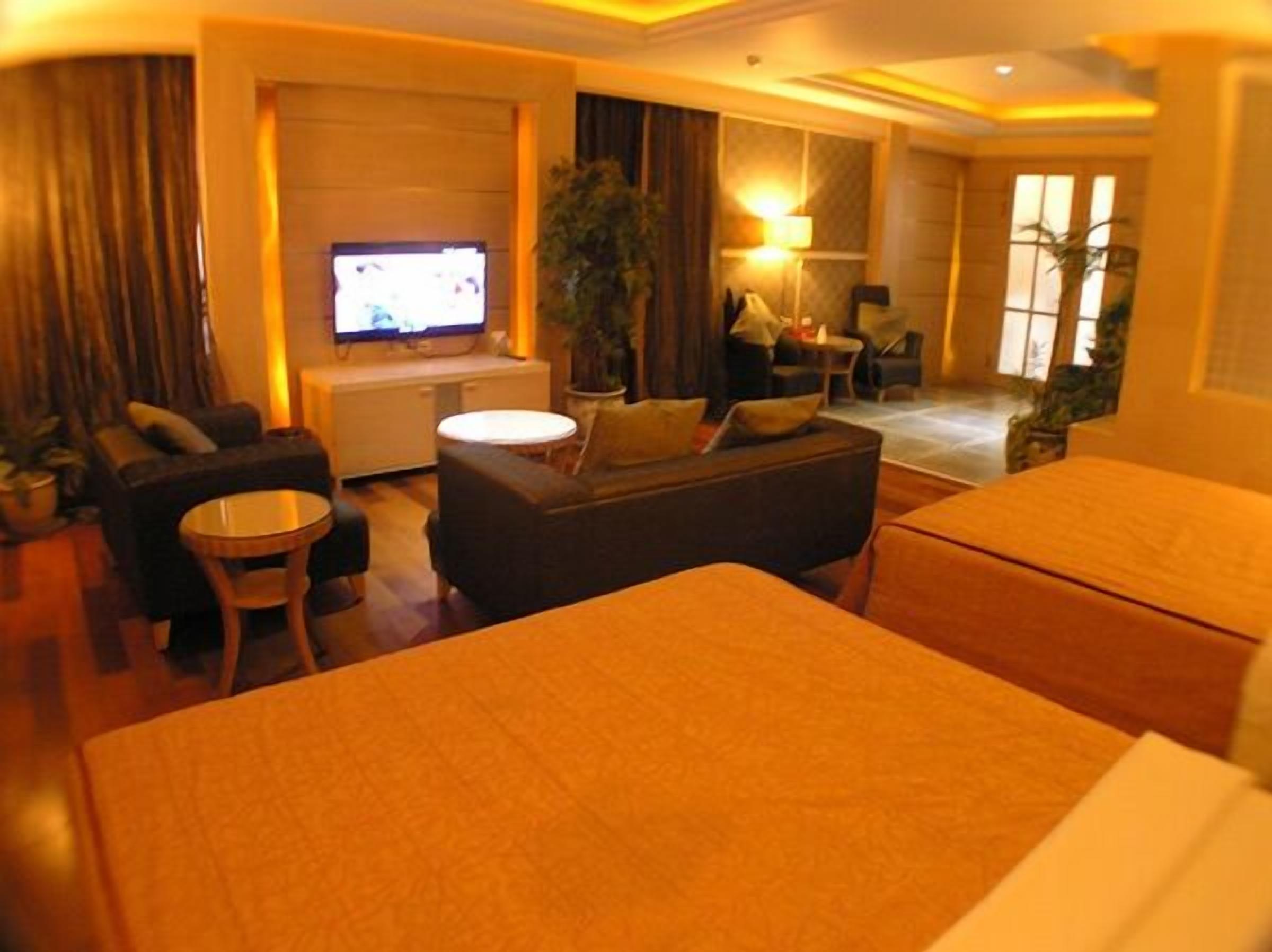 A hotel room with a bed, a sofa, a TV, a small table, and a chair.