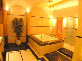A modern bathroom with a large bathtub, a potted plant, and a mirror.