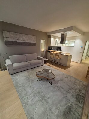 A modern living room with a grey sofa, a glass coffee table, and a grey rug. - Knokke- Albert Plage Superb 1 bedroom, 2a4per apartment 50m from the seaside, south facing (Knokke-Heist)