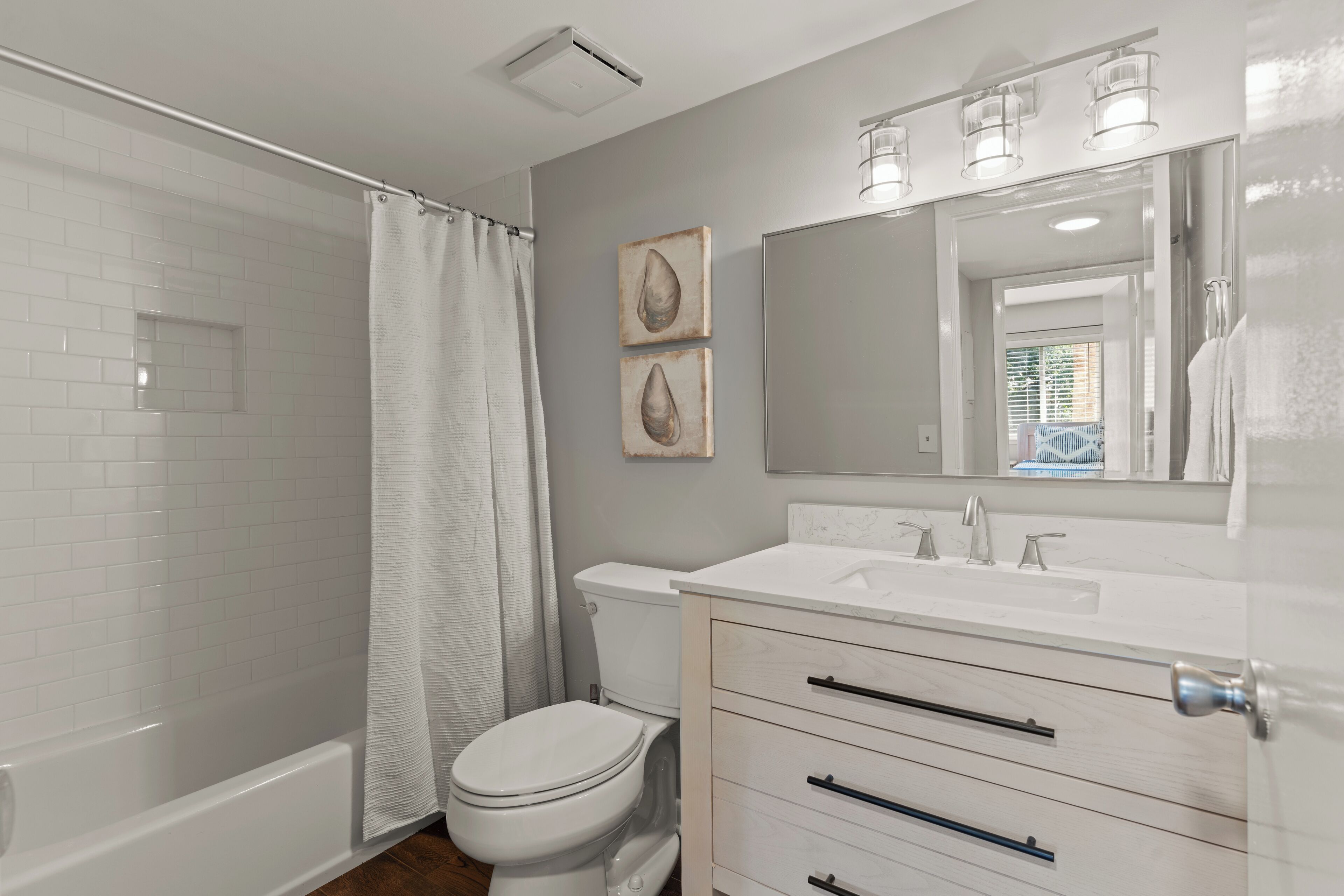 A bathroom with a shower, toilet, and vanity with a mirror.