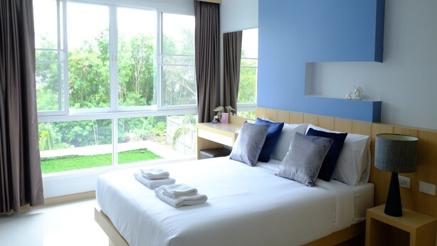 Een hotelkamer met een groot bed, een bureau en uitzicht op groen.