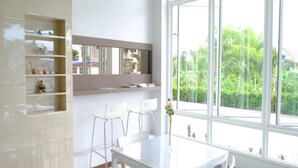 Een moderne keuken met witte kasten, een groot raam en een eethoek met witte stoelen.