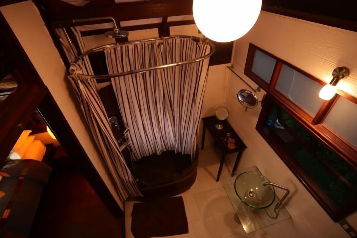 Une salle de bain avec un rideau de douche à rayures, un lavabo en verre et un meuble-lavabo en bois.