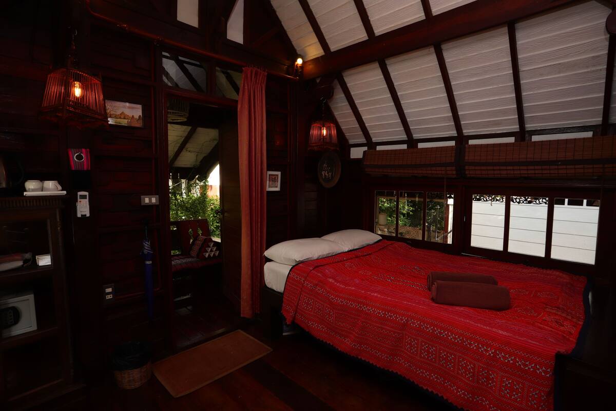 A cozy room with a large bed, wooden walls, and a sloped ceiling.